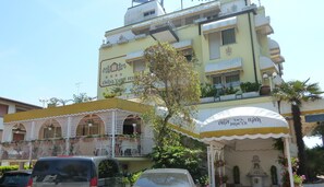 Un edificio con fachada amarilla, balcones con barandillas blancas y un letrero que dice "B&B del Mar".