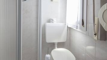 Un bagno moderno con box doccia in vetro, un water e un lavandino.