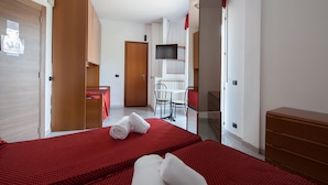 Una habitación de hotel con cama, escritorio, silla, televisor y armario.