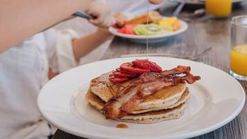 A breakfast plate with pancakes, strawberries, and bacon.