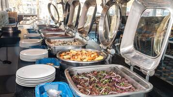 Una barra de buffet con diferentes recipientes de comida, platos y cubiertos.