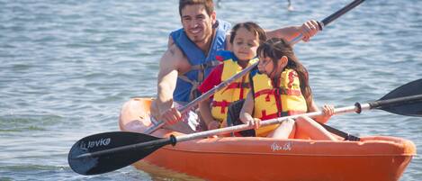 Una familia en un kayak naranja sobre aguas abiertas.