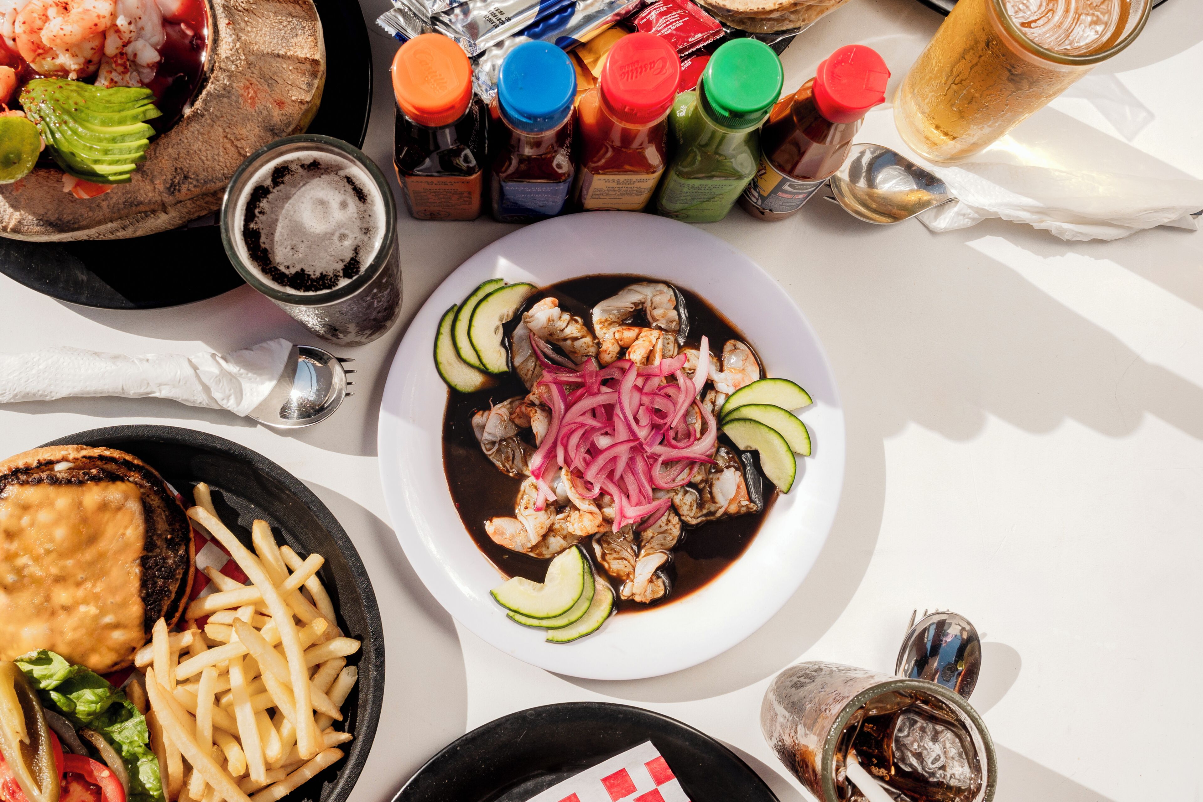 A table with a variety of dishes, condiments, and a drink.