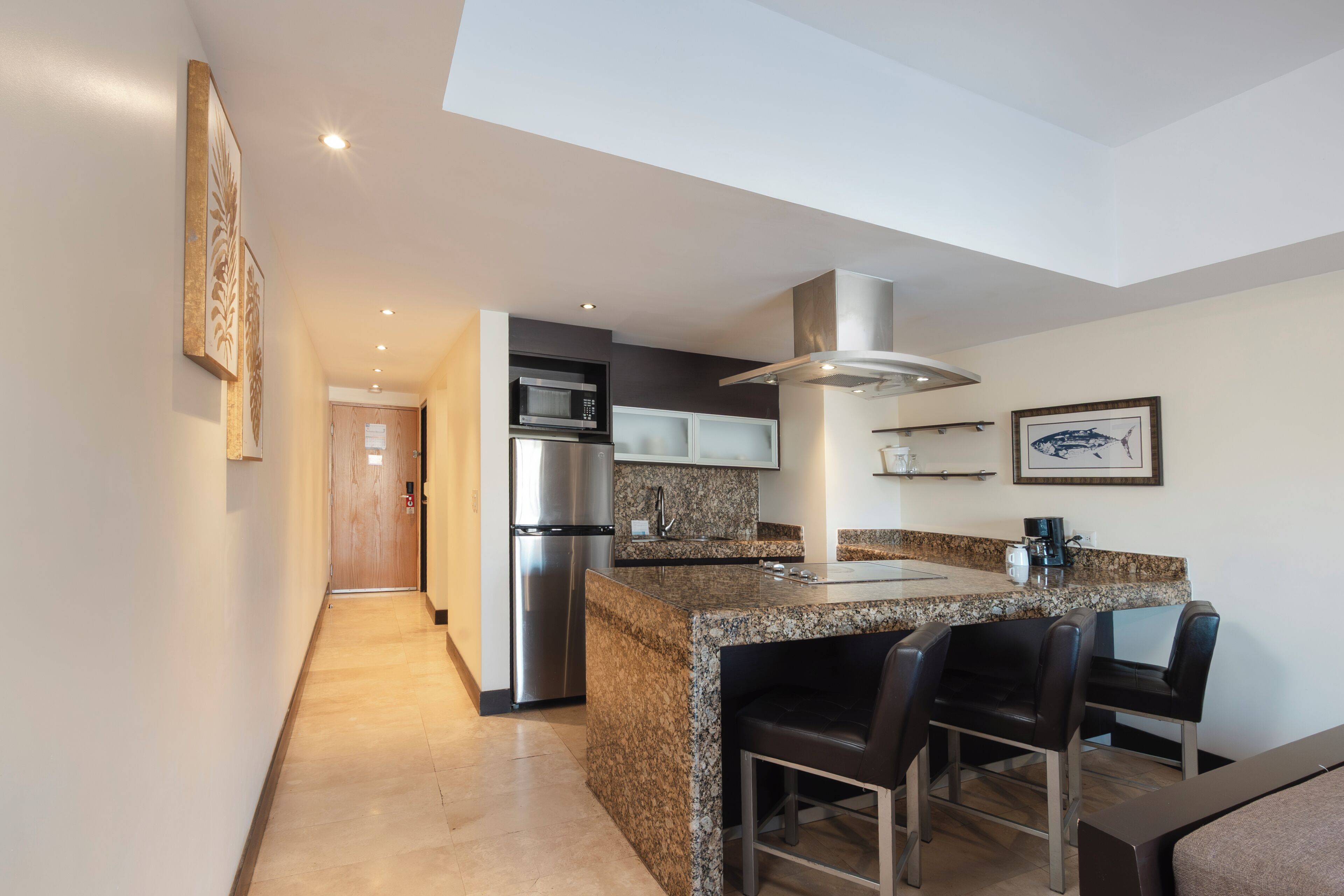A modern kitchen with granite countertops, stainless steel appliances, and a bar area.
