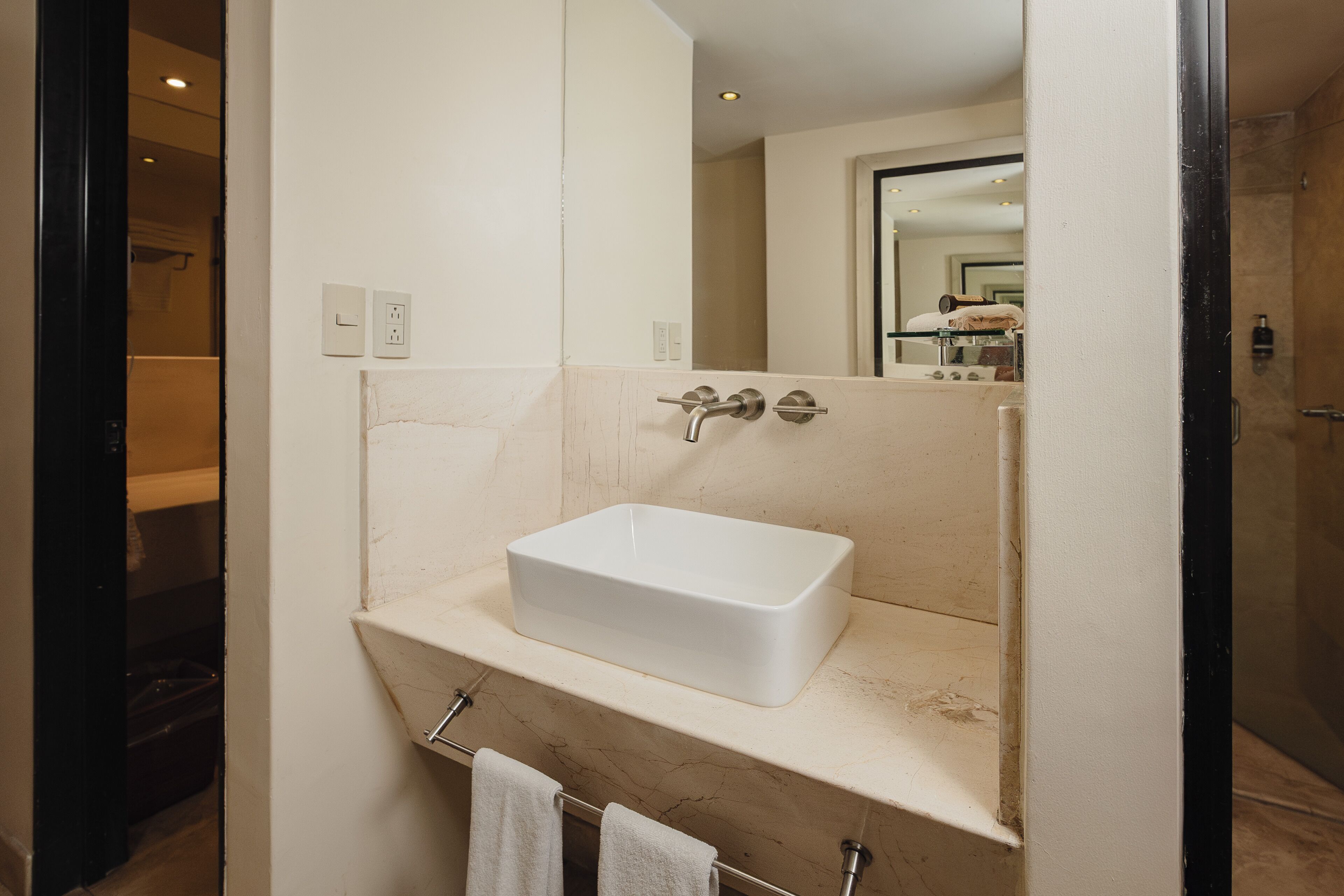 A bathroom with a white sink, a towel rack, and a mirror.