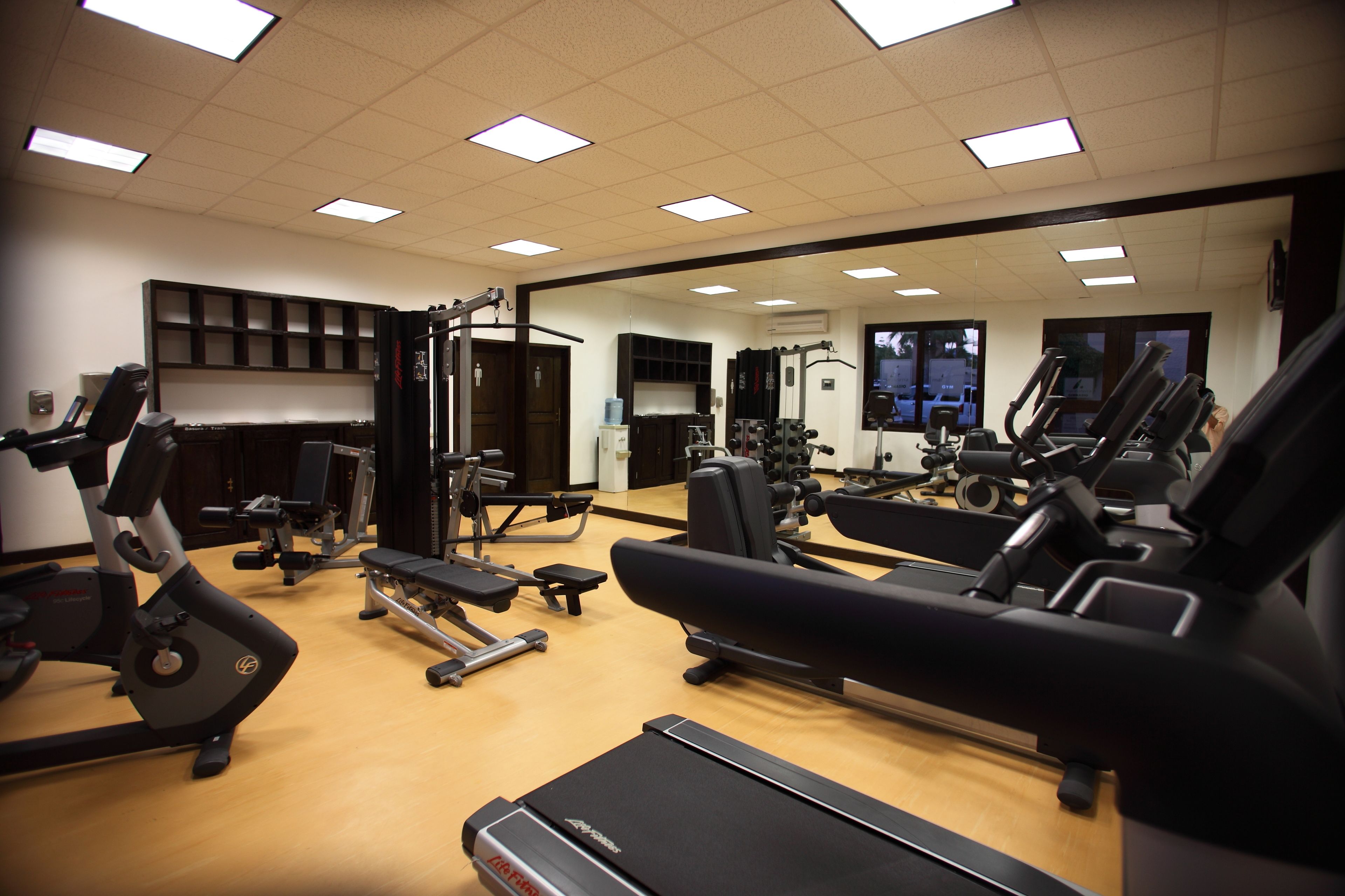 A gym with various exercise equipment, including treadmills, stationary bikes, and weight machines.