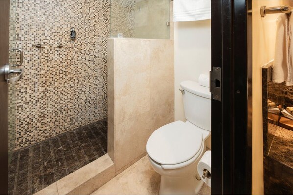A bathroom with a mosaic shower wall, a toilet, and a towel rack.