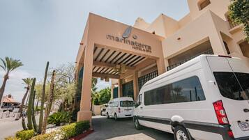 Entrada de un hotel con un cartel que dice 'Marinaterra Hotel & Spa', una camioneta blanca estacionada frente y un jardín de cactus.