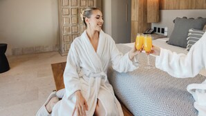 A hotel room with a bed, a wooden cabinet, a bedside table with a phone, and a patterned bedspread.
