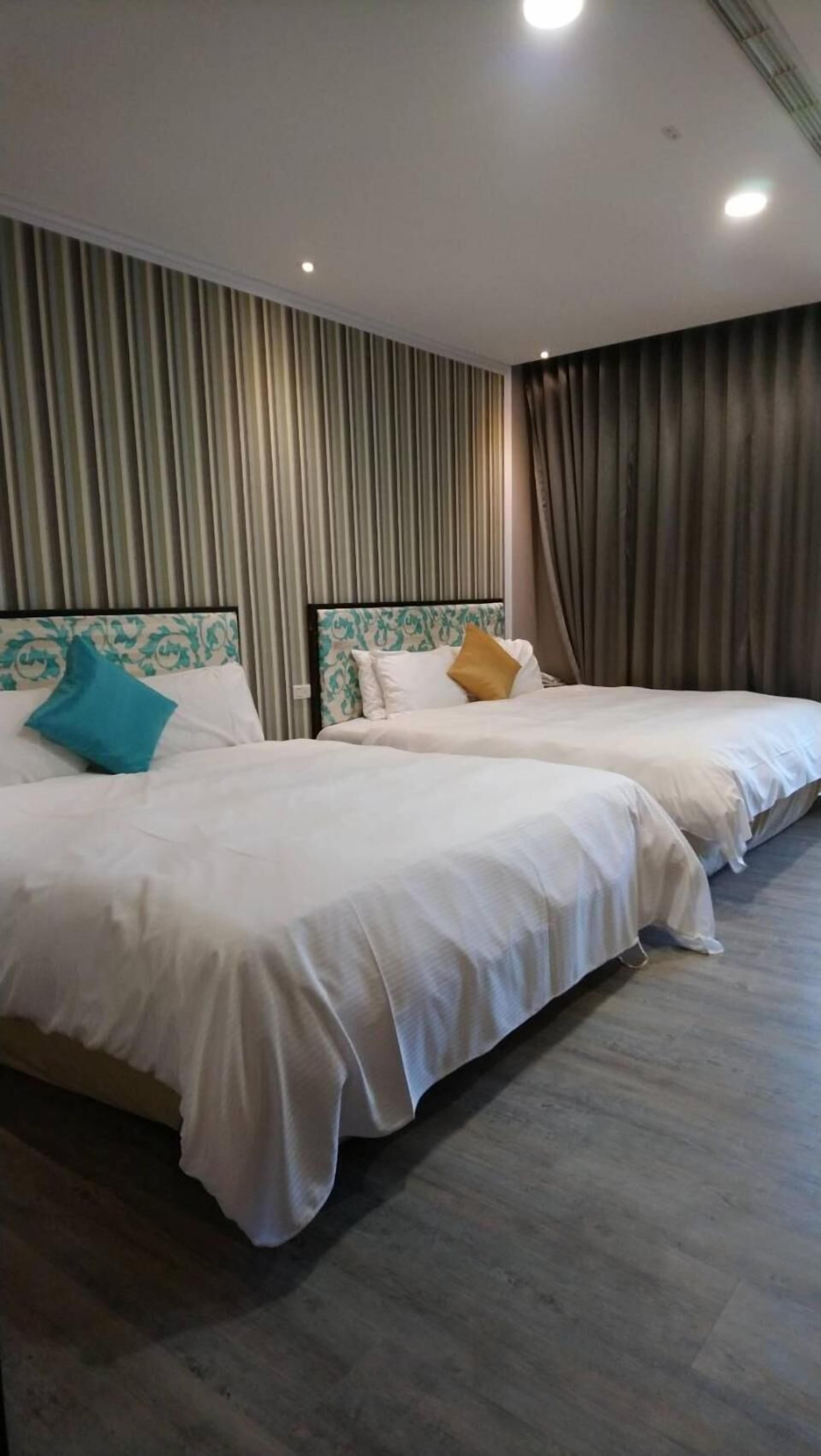 A hotel room with two beds, a striped wall, and a curtain.