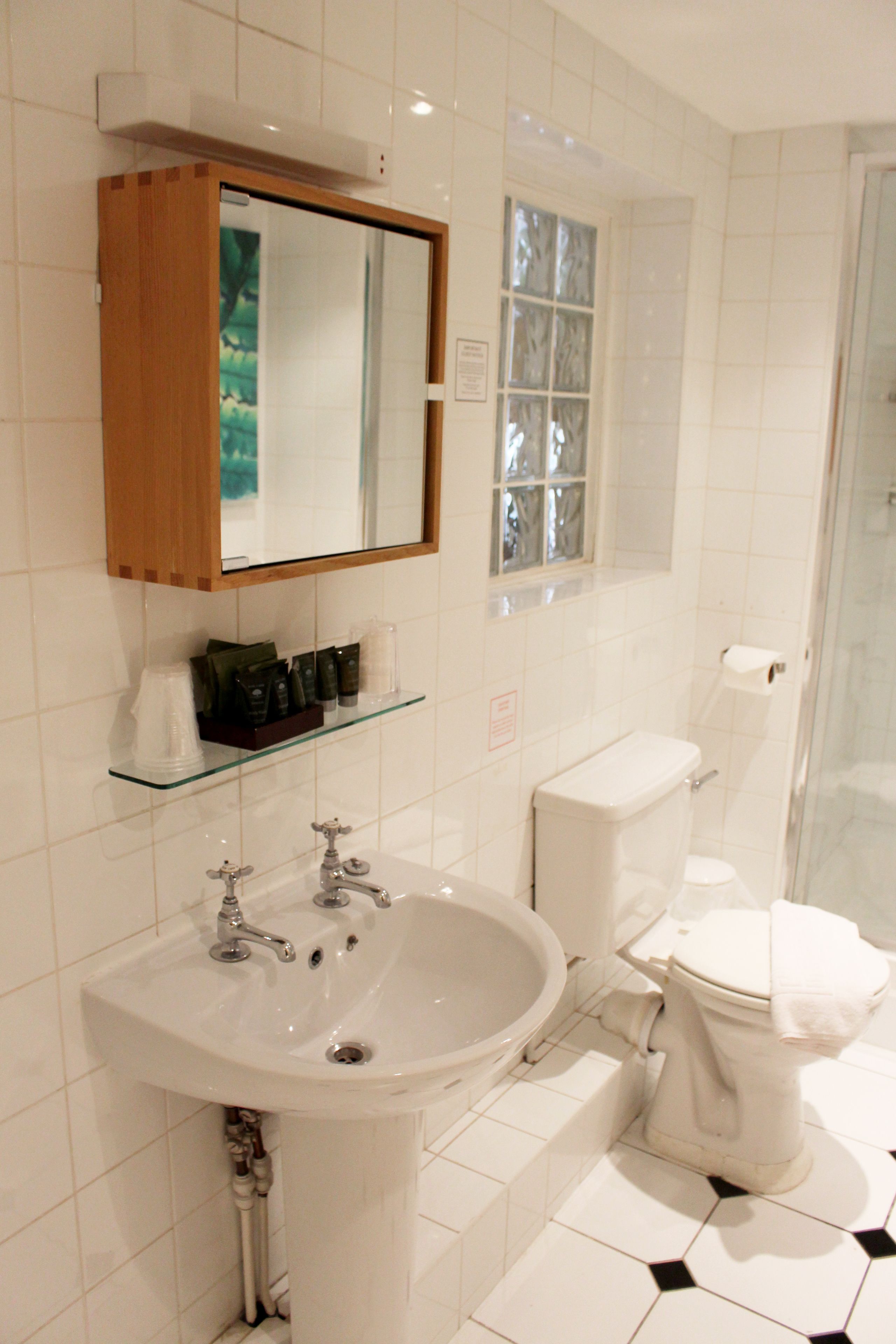 Ein Badezimmer mit weißem Waschbecken, einem Spiegel, einer Toilette und einer Duschkabine.