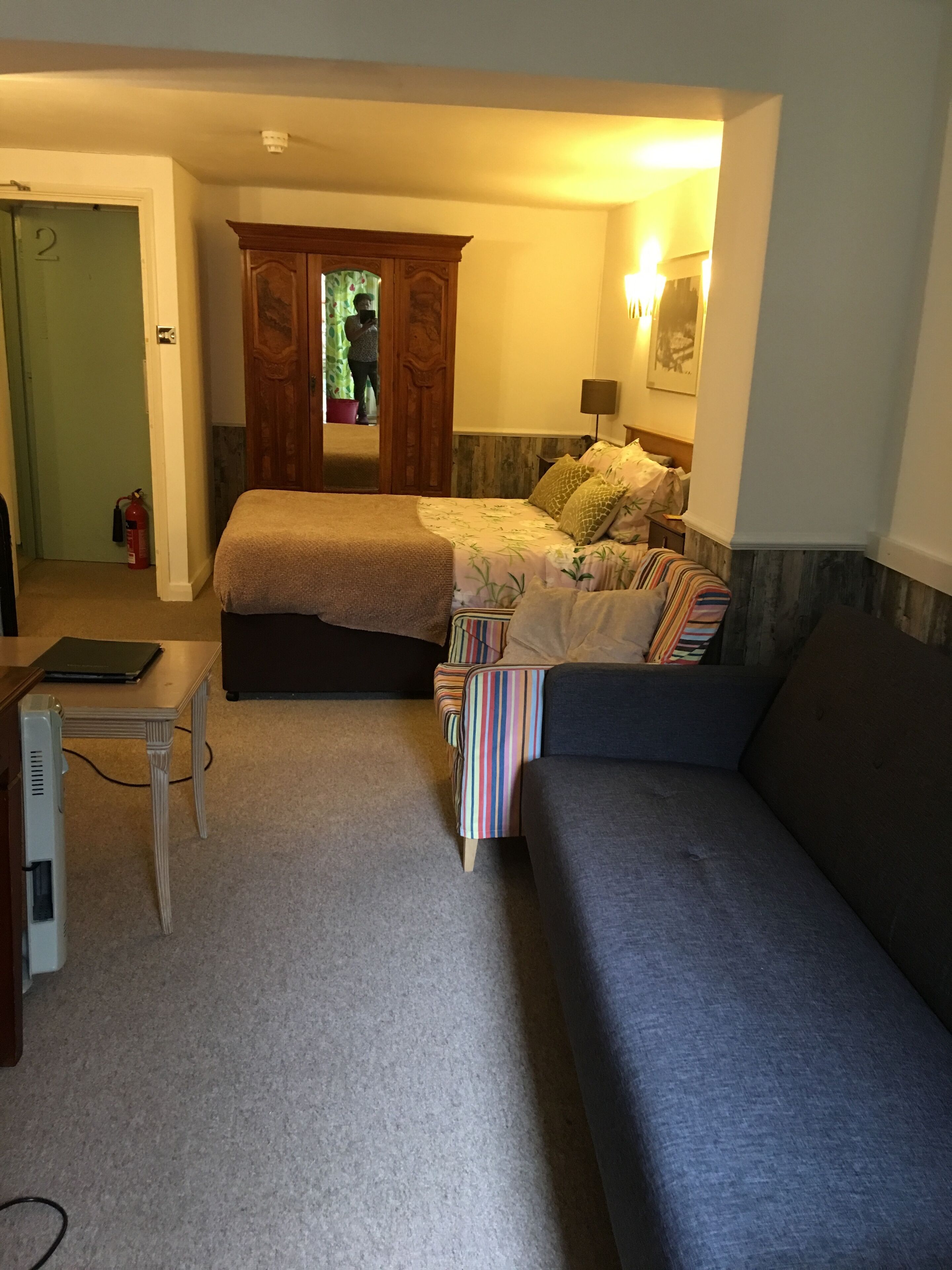 A bedroom with a bed, a sofa, a desk, and a wardrobe.