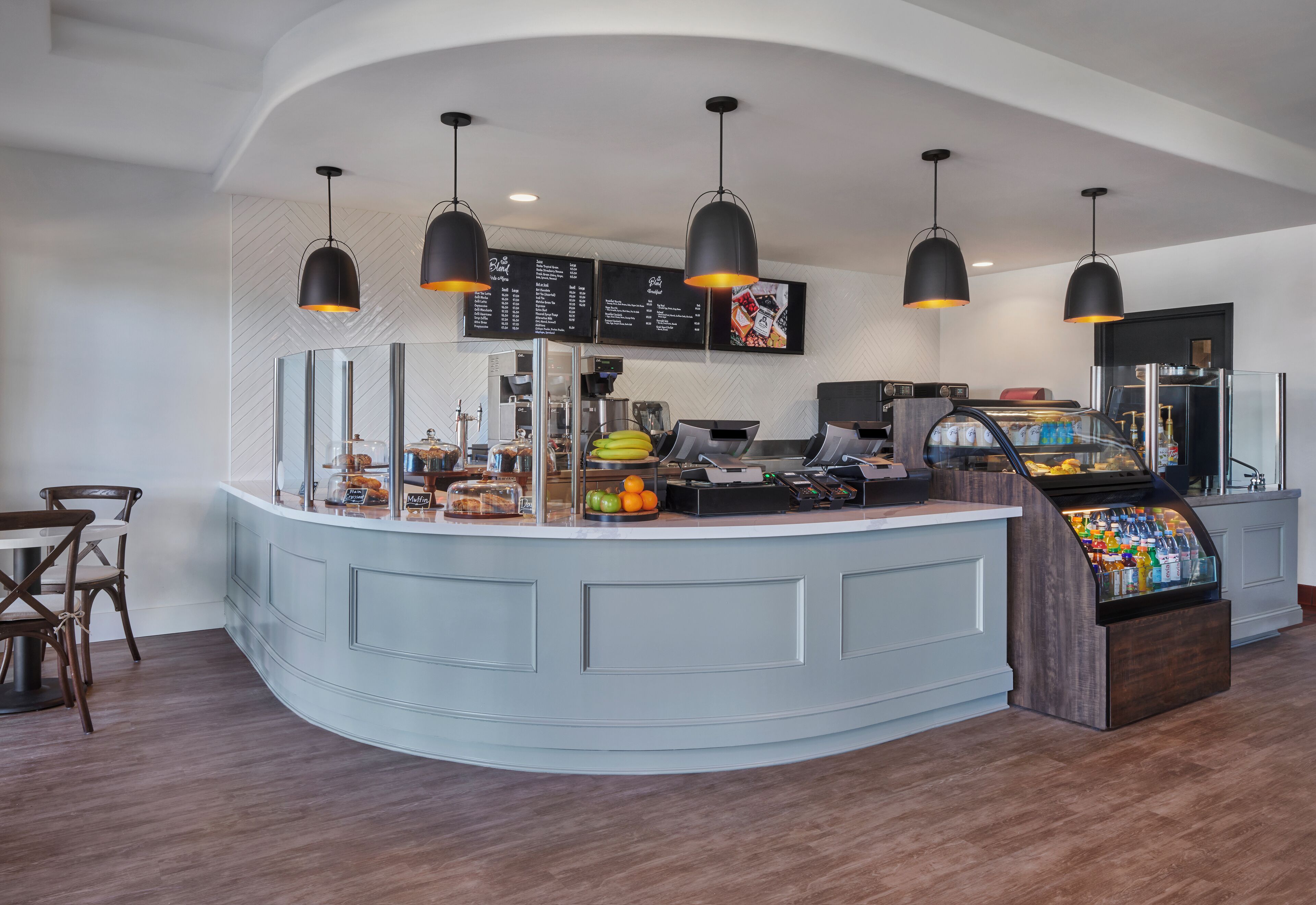 A modern counter with a menu board, a coffee machine, and a refrigerated display.