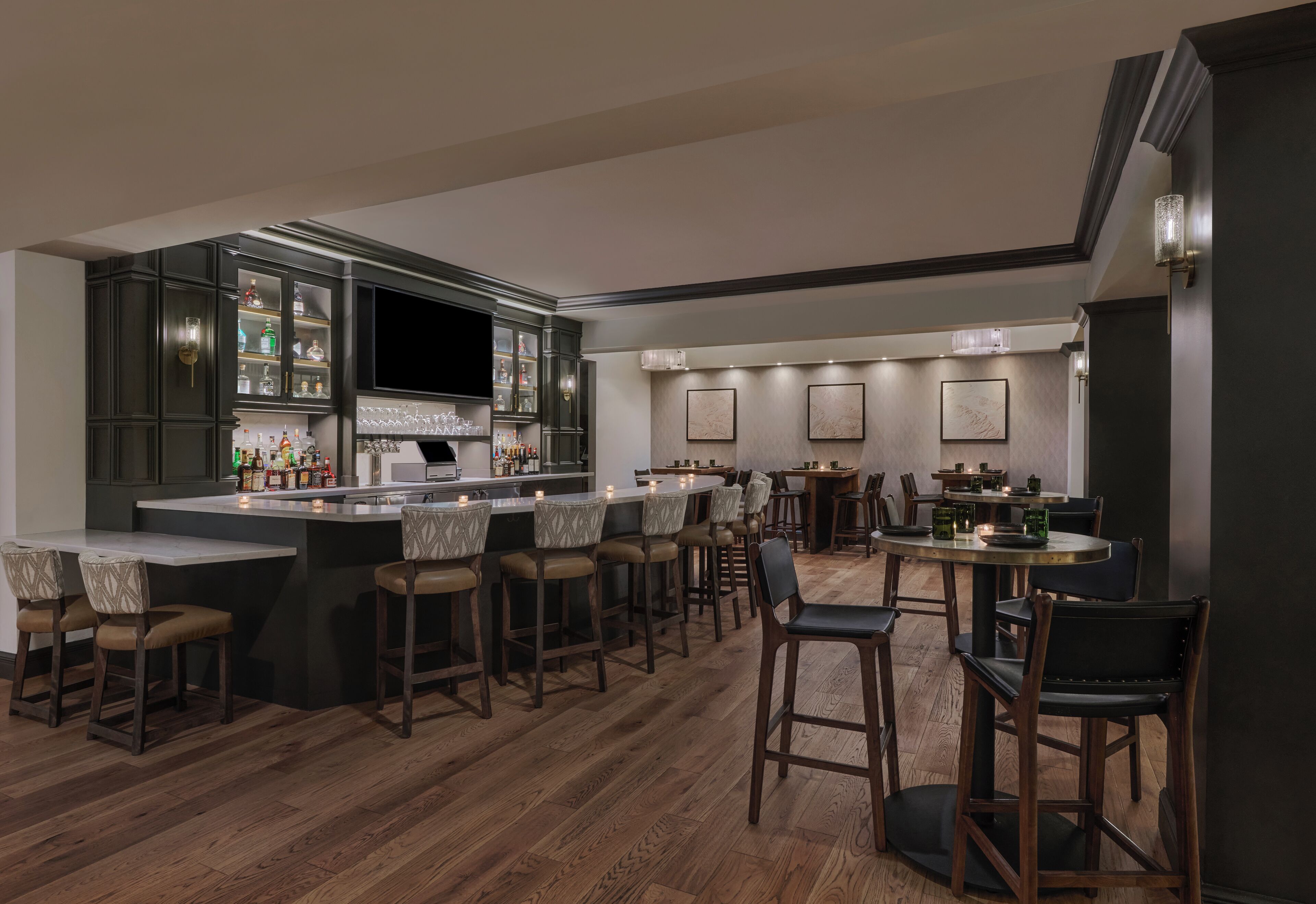 Une cuisine moderne avec un coin bar, un plancher en bois et des tabourets de bar.
