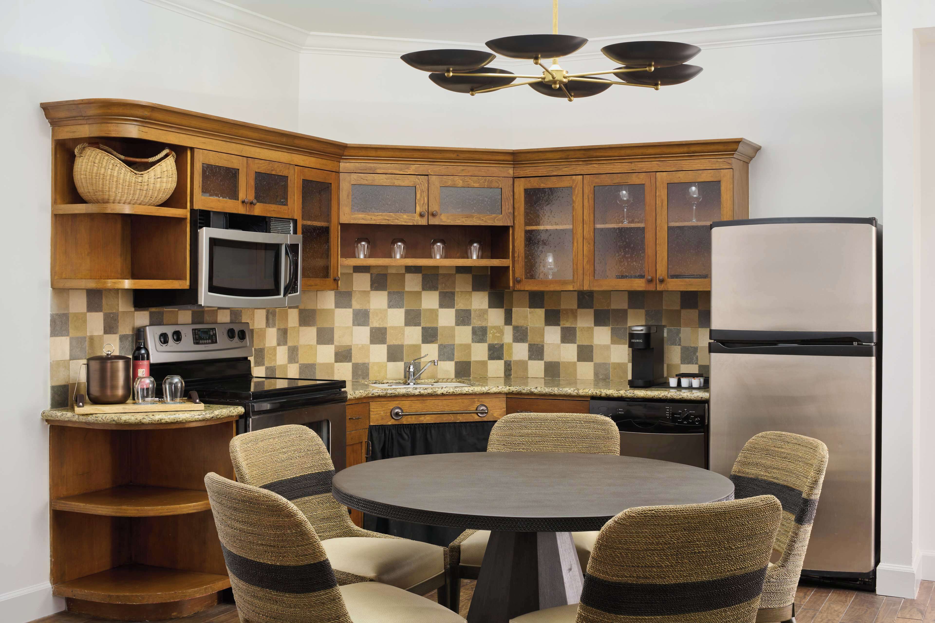 A kitchen with wooden cabinets, a microwave, a refrigerator, and a round dining table with chairs.
