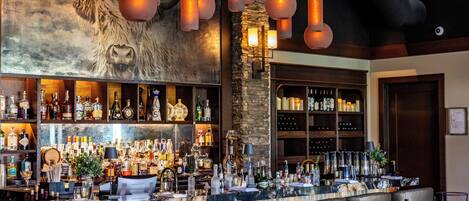 A bar with a long counter, multiple seating areas, and a large mural of a bull.