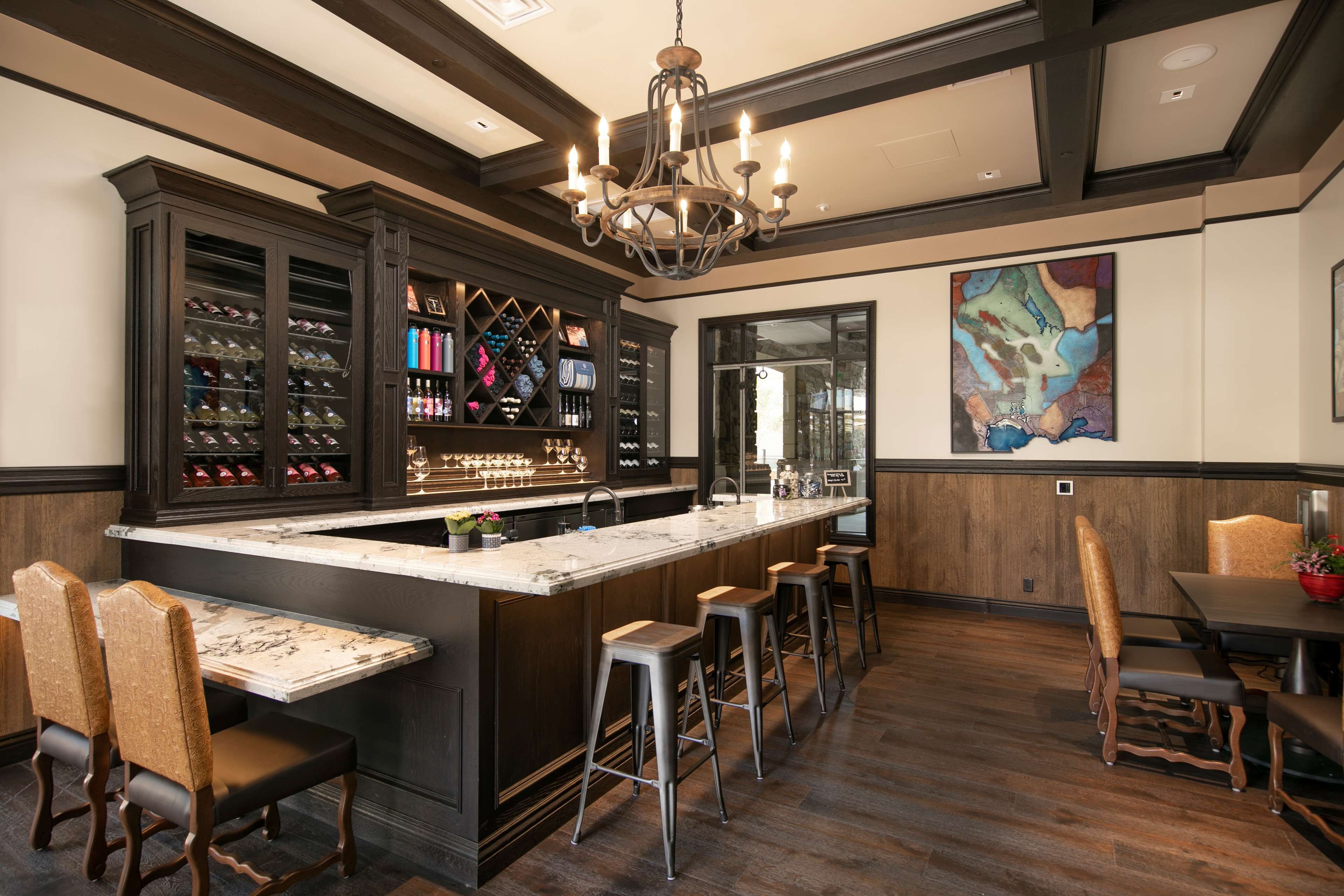 A bar area with a marble countertop, wooden bar stools, and a wine rack.