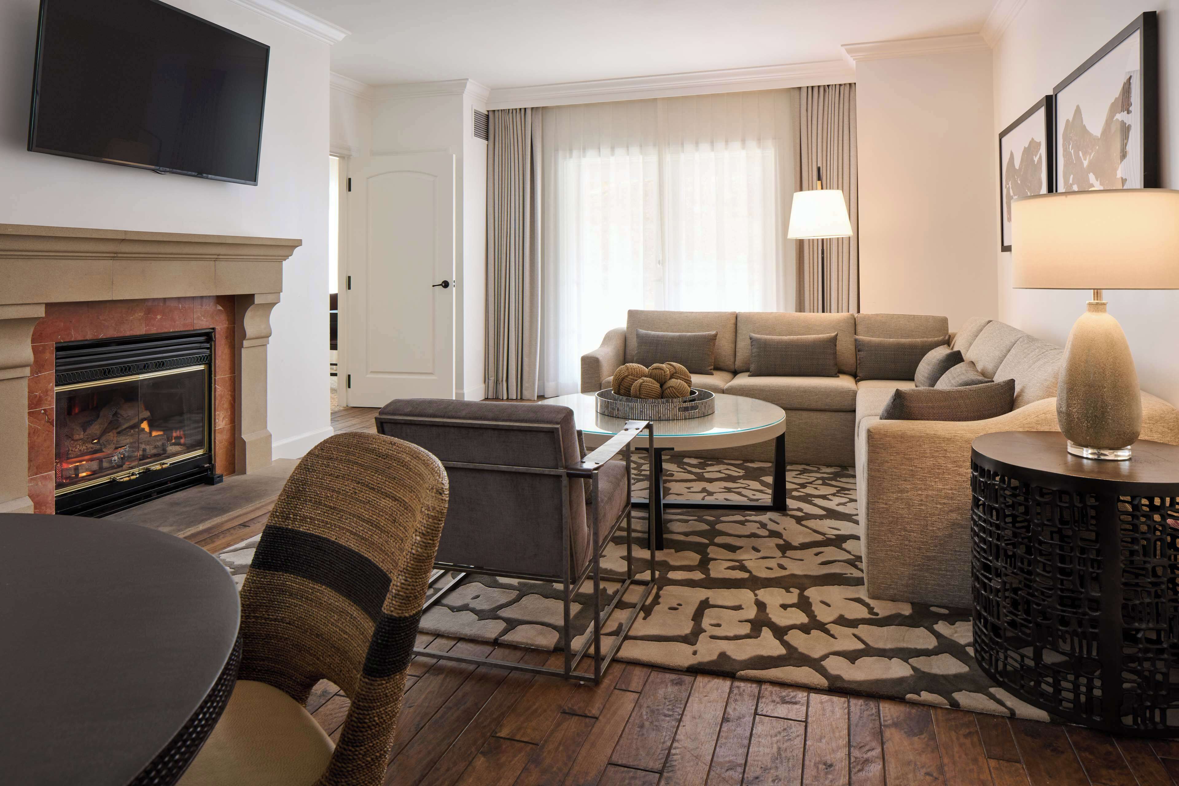 A living room with a fireplace, a sofa set, a coffee table, and a TV mounted on the wall.