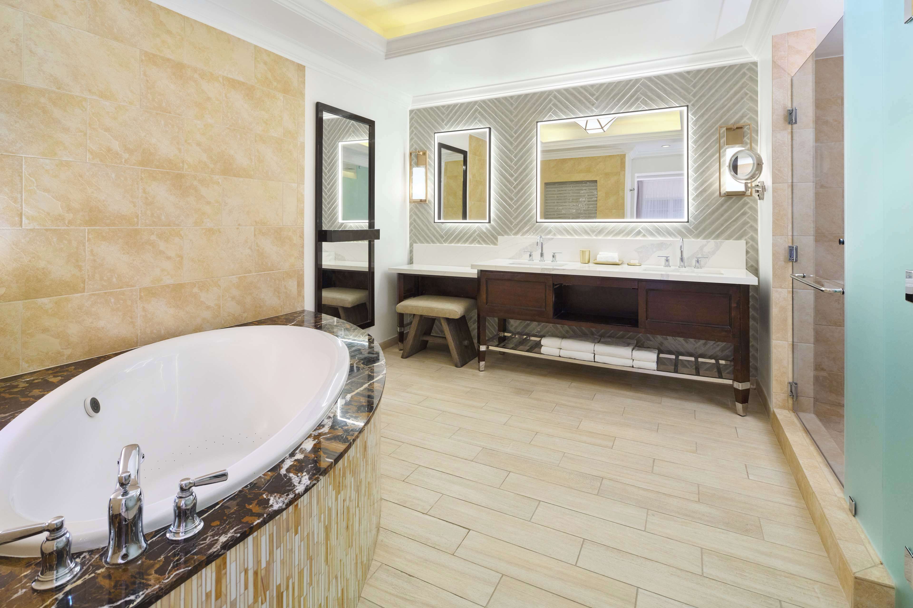 A modern bathroom with a large bathtub, a vanity with a mirror, and a shower area.
