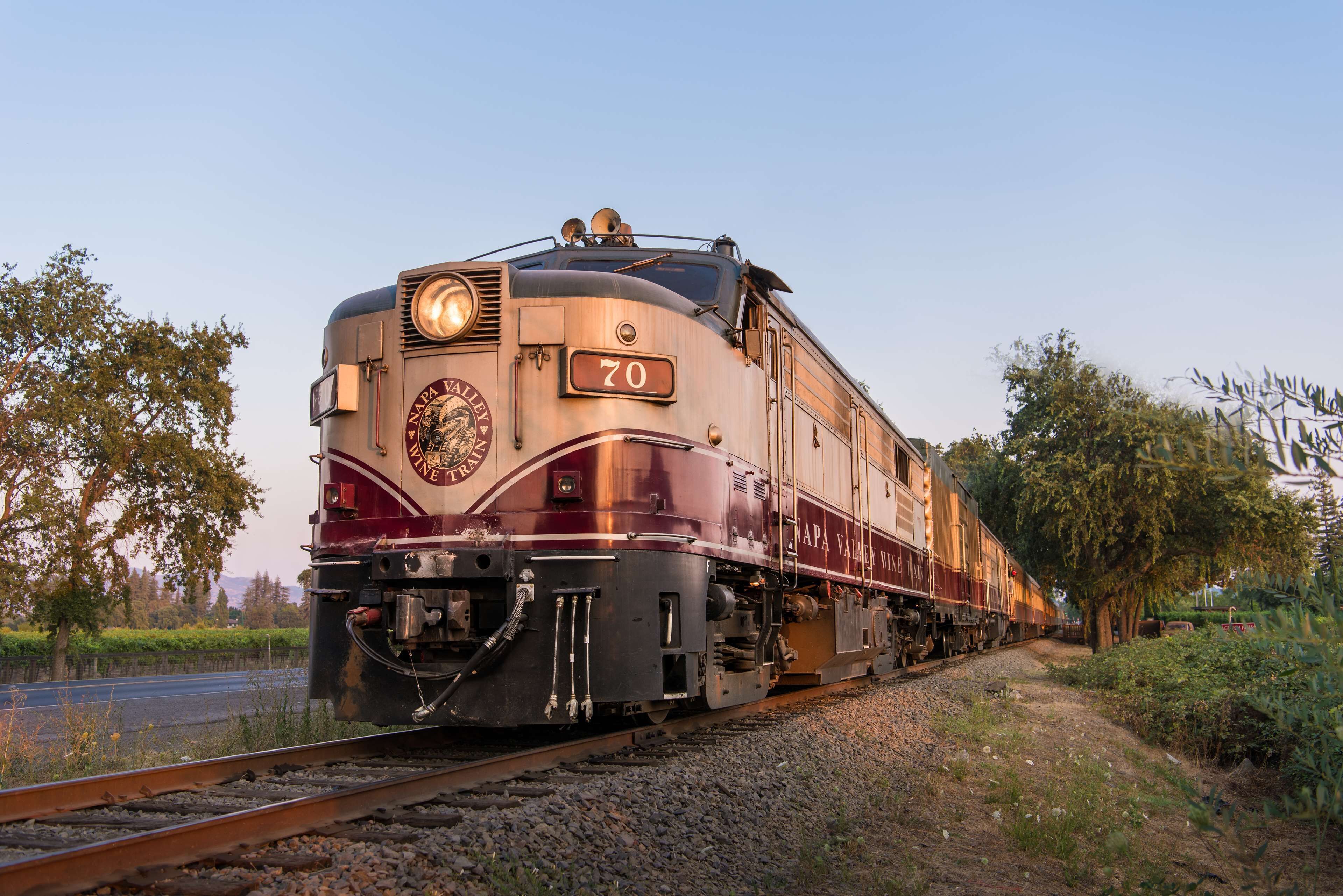 A train with the number 70 on its front, traveling on tracks surrounded by greenery.