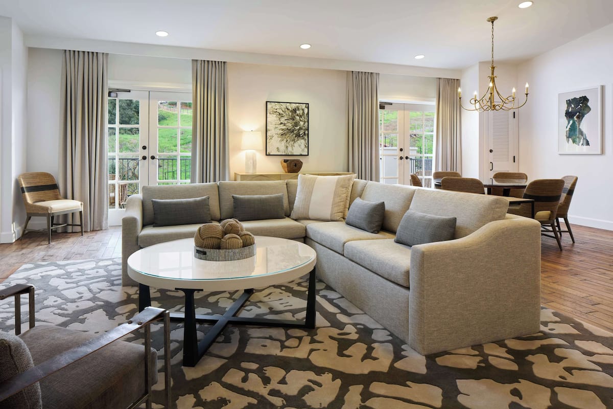 A modern living room with a sectional sofa, a glass coffee table, and a patterned rug.