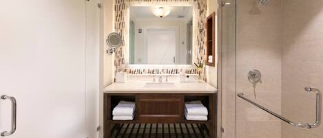 A modern bathroom with a shower, a sink with a mirror, and a towel rack.