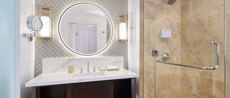 A modern bathroom with a large mirror, a vanity with a sink, and a glass-enclosed shower area.