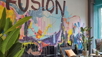 A modern living room with a large abstract painting, a comfortable lounge chair, and a potted plant.