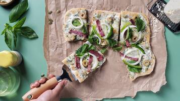 A hand cutting a pizza on a paper towel.