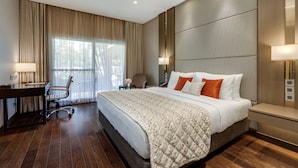 A modern hotel room with a large bed, a desk, and a chair. - Palm Meadows Resort (Bengaluru)