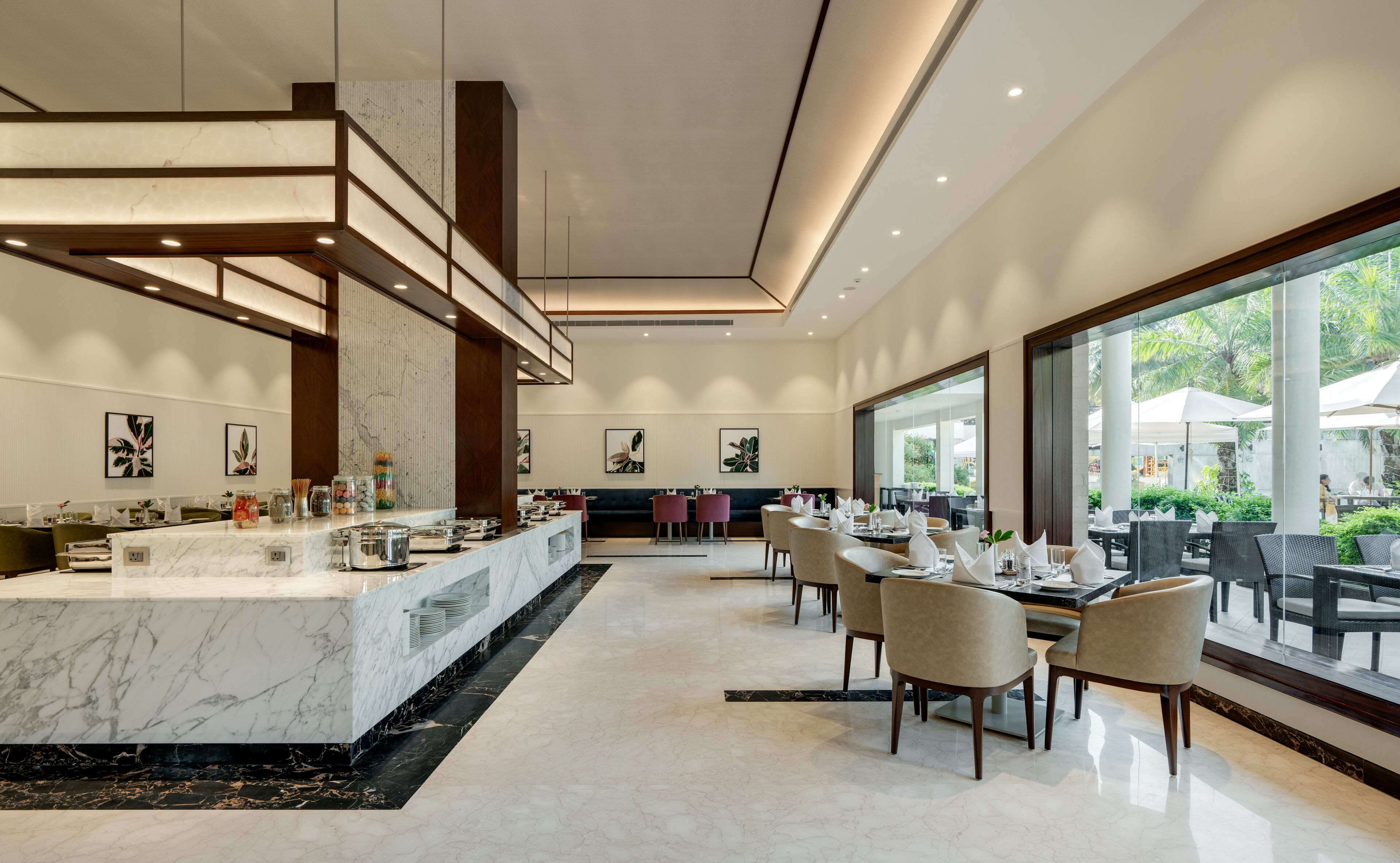 A modern restaurant with a marble bar, dining area with chairs, and large windows offering a view of the outdoors.