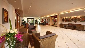 A spacious lobby with wicker furniture, a reception desk, and a large wall with decorative patterns. - Palm Meadows Resort (Bengaluru)