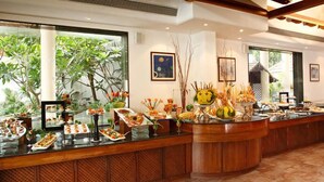 A buffet setup with various food items and a tropical view. - Palm Meadows Resort (Bengaluru)