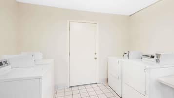 Un cuarto de lavandería con dos lavadoras de carga frontal, una secadora y una puerta.