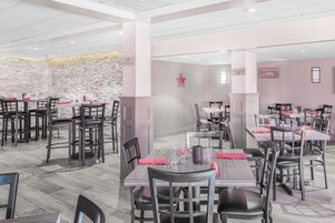 Un restaurante moderno con varias mesas y sillas, una pared de piedra y una estrella decorativa en la pared.