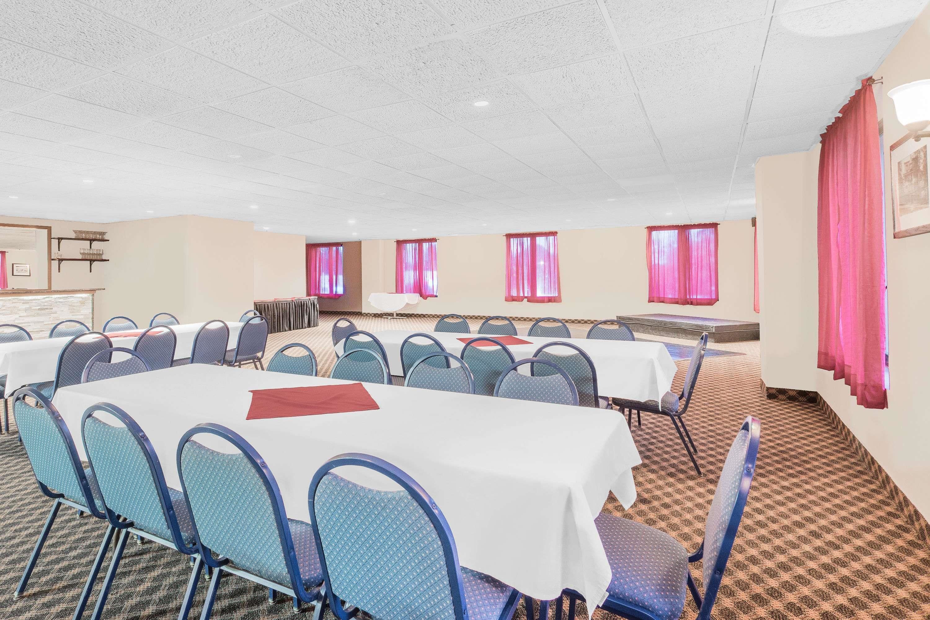 A conference room with multiple tables and chairs, arranged in rows.