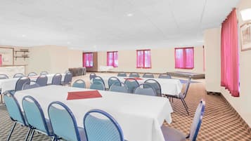 A conference room with multiple tables and chairs, arranged in rows.