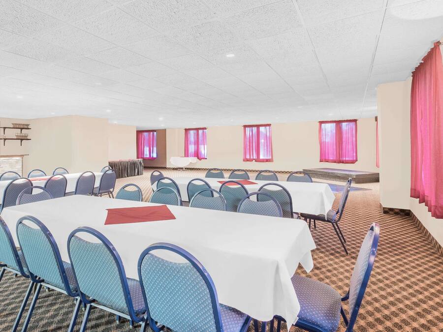A conference room with multiple tables and chairs, arranged in rows.