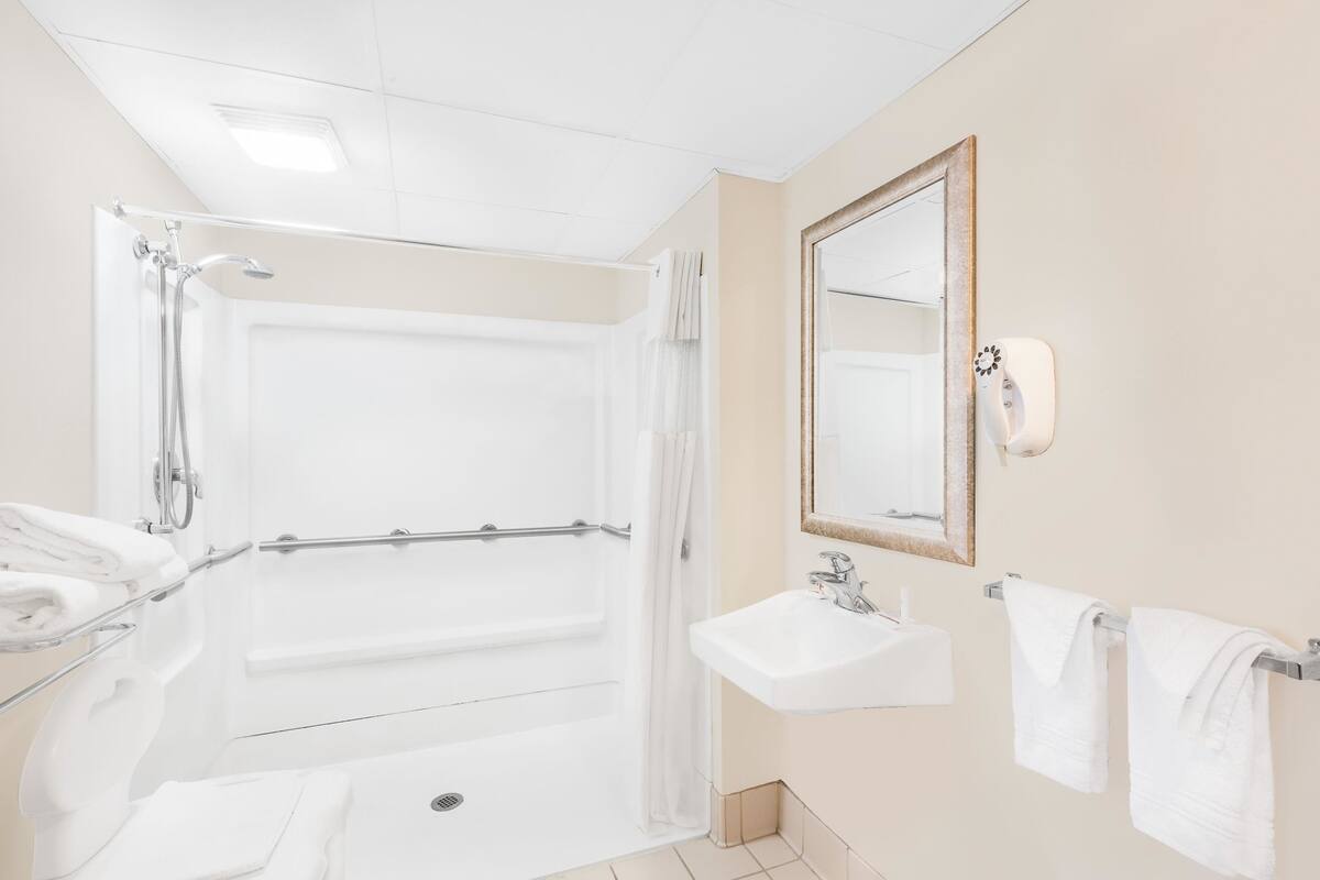 A modern bathroom with a shower, a sink, and a mirror.