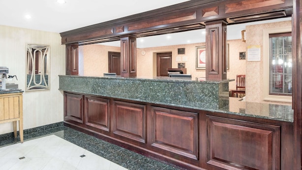 A reception area with a marble counter, wooden paneling, and a tiled floor. - Days Inn by Wyndham Springfield/Phil.Intl Airport (Springfield)