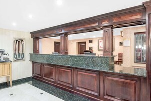 Una zona de recepción con mostrador de mármol, paneles de madera y suelo de baldosas.