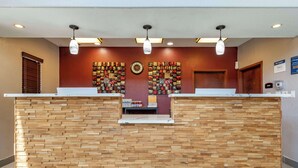 A reception desk with a wooden facade, a clock, and a wall of decorative items. - Best Western Plus Victoria Inn & Suites (Victoria)