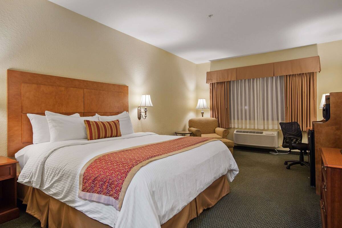 Hotelkamer met een groot bed, twee nachtkastjes, een bureau met stoel, een televisie en een airconditioning.