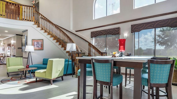 A spacious living area with a staircase, a dining table with chairs, and a sofa. - Best Western Plus Victoria Inn & Suites (Victoria)