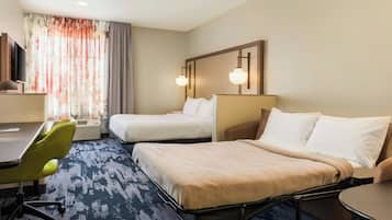 Une chambre d’hôtel avec deux lits, un bureau, une chaise et un téléviseur.