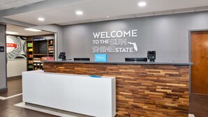 A reception desk with a "Welcome to the Sun Shine State" sign, a wooden wall, and a minibar. - Hampton Inn & Suites - Cape Coral/Fort Myers Area, FL (Cape Coral)