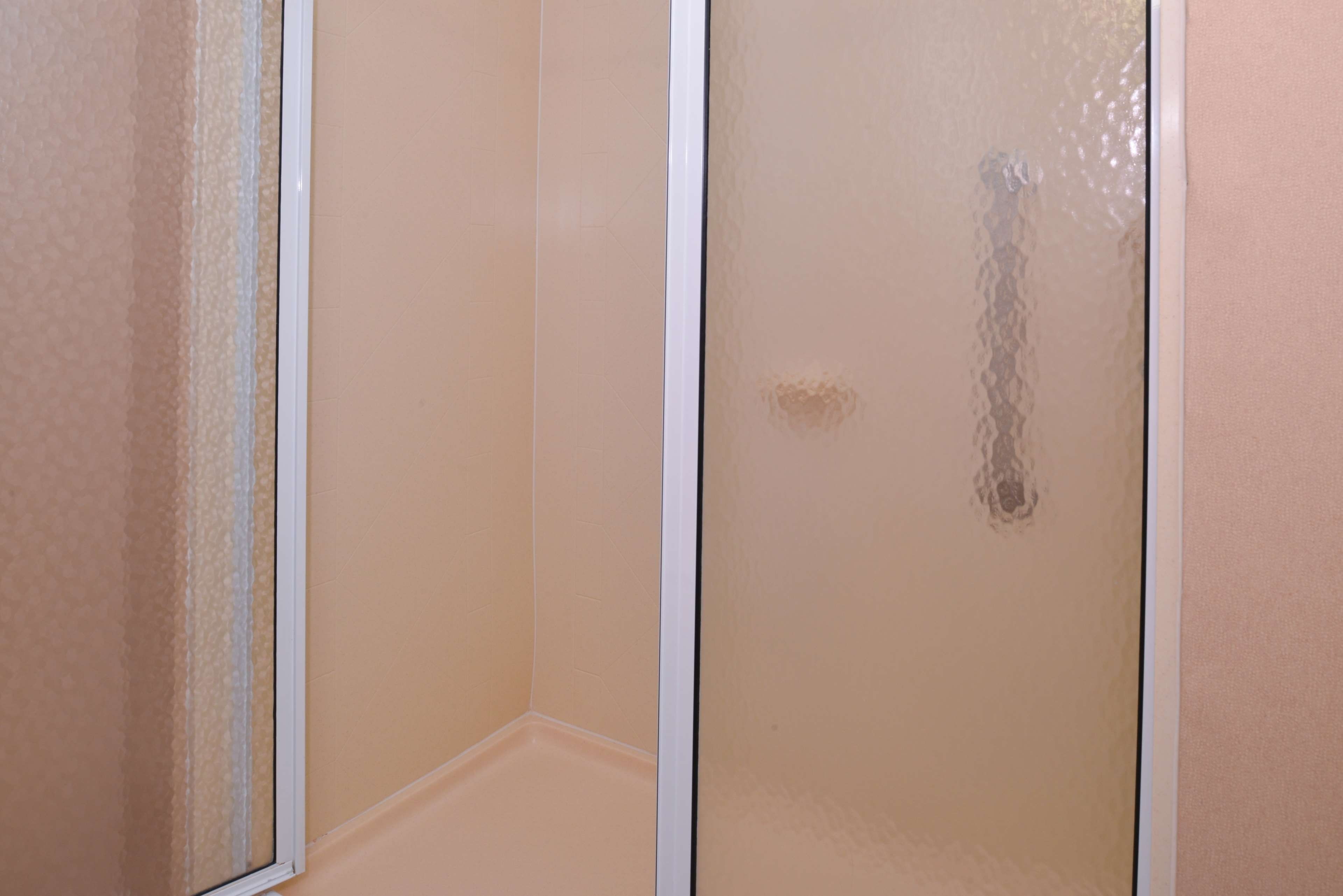 A bathroom with a shower enclosure and a visible drain.