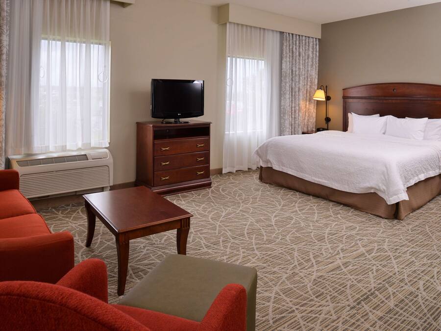A hotel room with a bed, a television, a dresser, and a seating area with chairs.