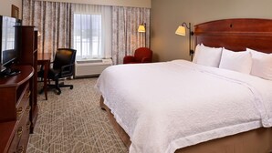 A hotel room with a large bed, a desk with a television, a chair, and a window with curtains. - Hampton Inn by Hilton Litchfield (Litchfield)