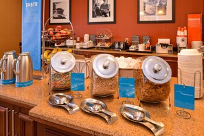 Zona de bufé con diversas opciones de comida y utensilios.